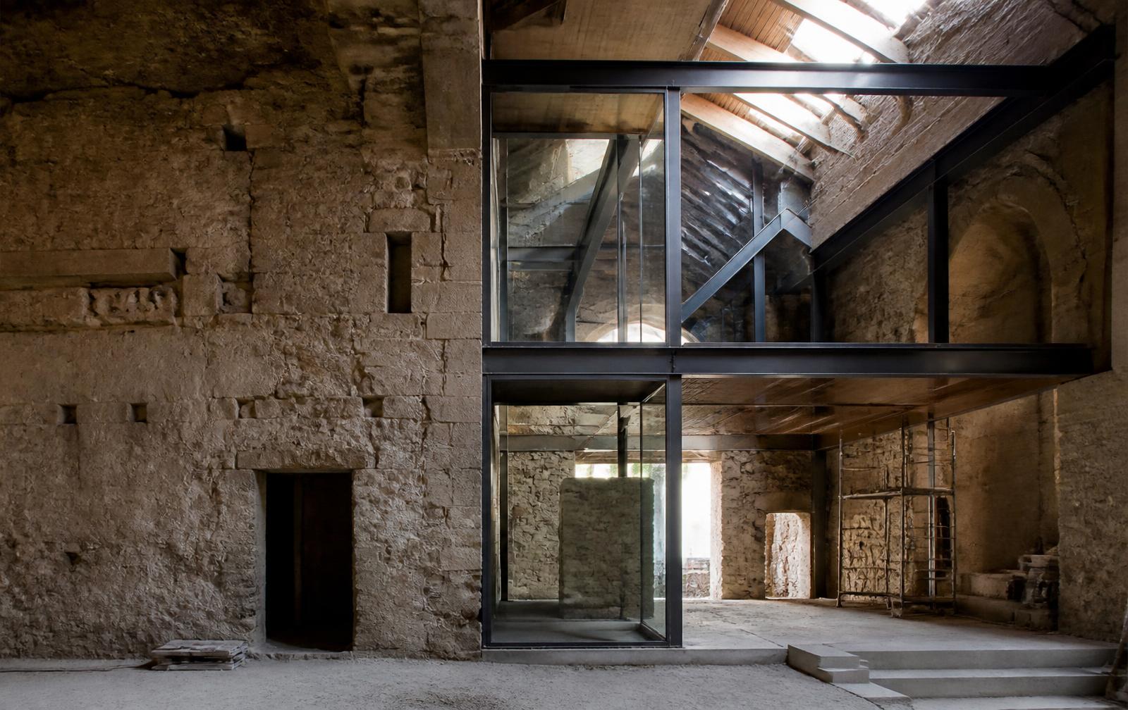 Bâtiment ancien en pierre réhabilité : insertion contemporaine acier et verre dans les murs existants